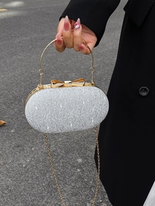 Pochette de soirée ovale argentée à texture melon, fermoir nœud d'or et poignée anneau
