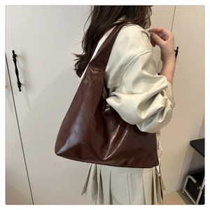 Detail of deep brown glossy leather tote bag showing large capacity and smooth texture