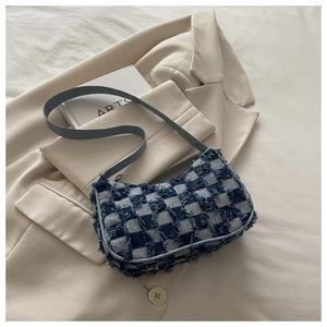 Détail du sac à damier bleu avec bords effilochés sur un blazer beige élégant