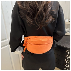 Detail of orange nylon waist bag showing double zipper compartments and woven rope pullers