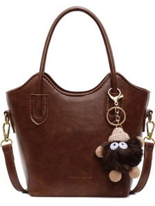 Borsa a secchiello marrone scuro con manici e un divertente ciondolo mostro di peluche