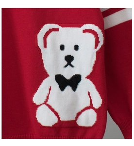 Detail shot of a red knitted sweater featuring a large white bear with a black bow tie