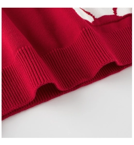 Detailed close-up of red ribbed knit hem and white bear pattern on children's sweater