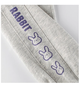 Dettaglio dei pantaloni grigi per bambini con stampe di conigli viola e testo sul lato
