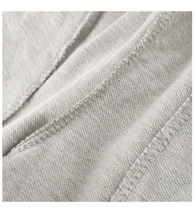 Dettaglio macro del tessuto French Terry grigio e cuciture precise sui pantaloni da bambina