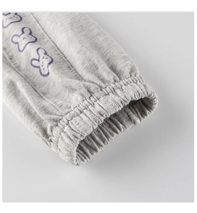 Dettaglio dei pantaloni in maglia grigia con polsini a costine e stampa orso viola
