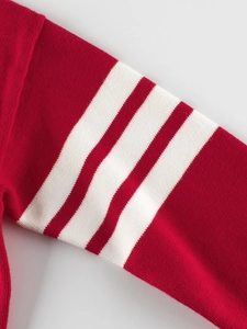 Close-up of red knit sweater sleeve with three white stripes in classic varsity style