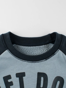 Close-up of children's blue fleece sweatshirt showing ribbed crewneck and warm lining