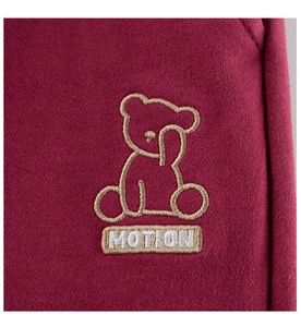 Détail de la broderie d'ours et texte MOTION sur un tissu en coton tricoté bordeaux
