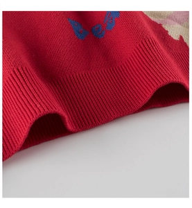 Close-up of red knit sweater featuring a ribbed hem and blue decorative lettering detail