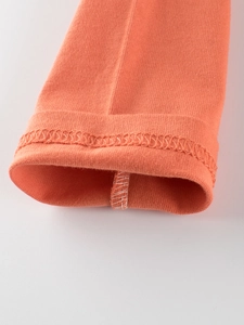 Close-up of orange long-sleeve T-shirt sleeve cuff with detailed knit texture and stitching
