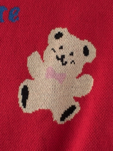 Children's red knit sweater featuring a cute white bear pattern with pink bow detail