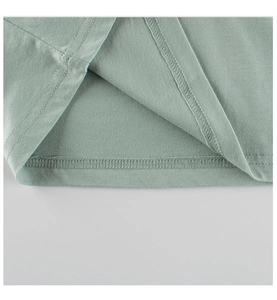 Close-up of double-stitched hem and fine cotton fabric on kids' green t-shirt