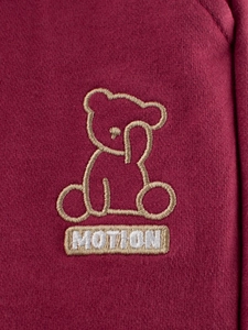 Gros plan sur le pantalon tricoté bordeaux pour enfant avec broderie ours MOTION