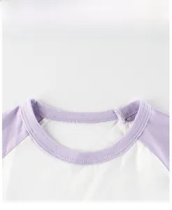 Détail du col rond et des manches raglan sur un t-shirt en coton blanc et violet pour enfant