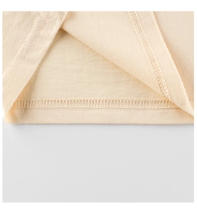 Détail de couture à double aiguille sur l'ourlet d'un t-shirt beige en coton pour enfant