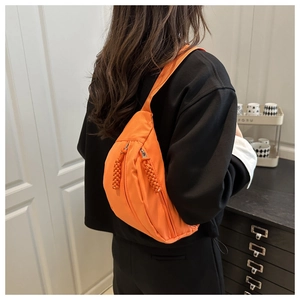 Achteraanzicht van een model met een feloranje nylon halve maan crossbody tas
