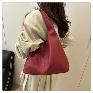 Detailed back view of a large red textured leather tote bag on a female model