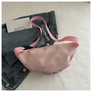 Detail of pink half-moon crossbody bag with adjustable strap and buckle on blue denim