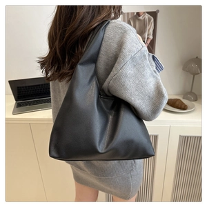 Chic black pebbled leather tote bag worn as a shoulder bag in a modern interior setting
