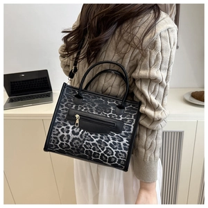 Detail of leopard print handbag showing black trim and adjustable shoulder strap