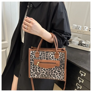 Detail of leopard print tote with brown leather handles and a front zipper pocket