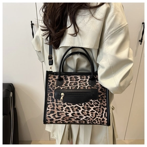 Detail of leopard print tote bag featuring a front black zipper pocket and sturdy handles