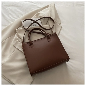 Detail of the high-quality dark brown leather handle and shoulder strap on a chic tote