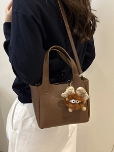 Borsa a mano marrone in pelle con ciondolo di peluche e sottile tracolla da donna