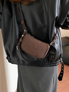 Minimalist coffee brown crossbody bag with knot strap shown on shoulder with leather jacket