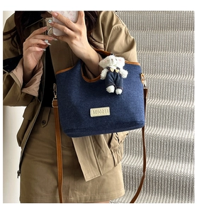 Detail der dunkelblauen Jeans-Tasche mit Lederbesatz und süßem Bärenanhänger