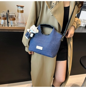Detail der Denim-Handtasche mit 3D-Plüschbär-Anhänger und hochwertigem Leder-Markenlogo