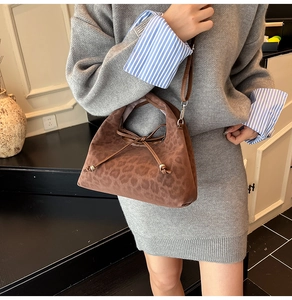 Detail of a brown leopard print hobo bag with drawstring closure and slim shoulder strap