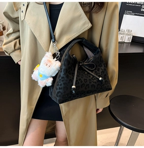 Detail of leopard print bag with drawstring closure and a plush bear pendant