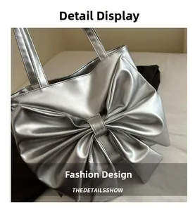 Detail shot of a silver mirror tote bag featuring a large decorative bow and slim strap