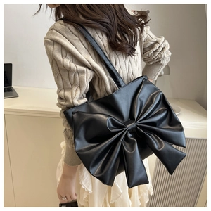 Detailed view of black tote bag featuring a large decorative bow and soft matte texture
