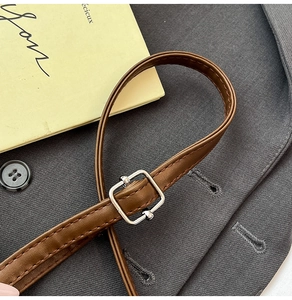Close-up of brown leather strap with silver buckle and fine stitching on a handbag