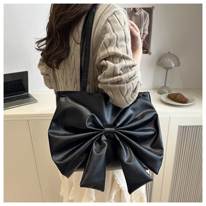Detail of a black PU leather shoulder bag featuring a large decorative bow design