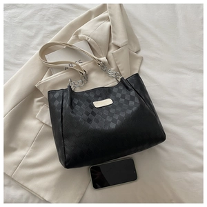 Close-up of black checkered embossed tote bag featuring metal chain and leather straps