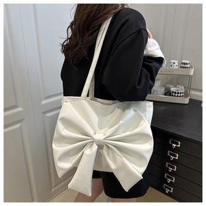 Close-up of stylish white tote bag with oversized decorative bow and premium PU leather texture