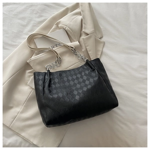Detail of black checkered embossed tote bag with leather and silver chain strap