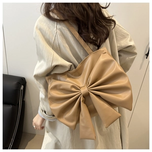 Detail of elegant beige bow-shaped tote bag worn by a model in a minimalist setting