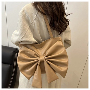 Detail of light coffee tote bag featuring large bow design and matte PU leather finish