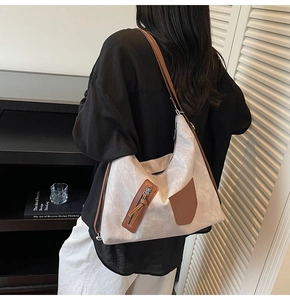 Detail of grey tote bag with brown leather accents and side zipper pocket for casual style