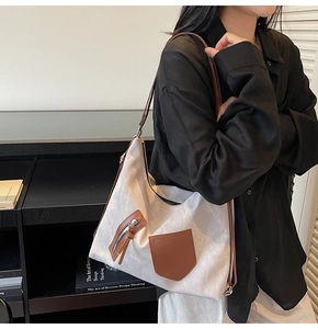 Close-up of large canvas tote with brown leather pockets and adjustable shoulder strap