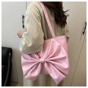 Close-up of pink bow tote bag with shiny PU leather texture shown on shoulder