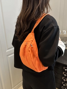 Bright orange nylon crossbody fanny pack for women shown as a model back view