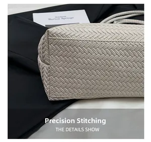 Detailed close-up of precise stitching on beige woven tote bag with a minimalist design