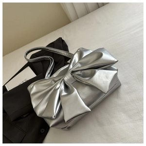 Detail view of a large bow on the metallic silver tote bag with silk-like finish