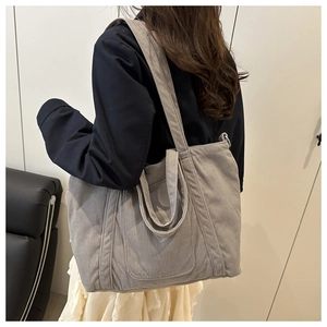 Detail view of large grey corduroy tote bag worn over shoulder with a casual chic outfit